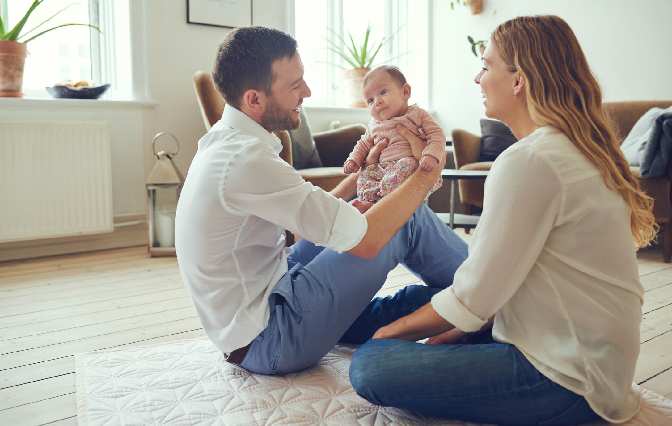 comfortable mother and father play with child on living room floor